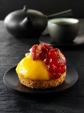 Fruit cake with fruits and creme patisserie in a black Japanese tea setting