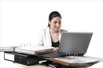 Office worker sitting at a desk with file folders and a laptop