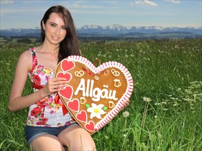 Woman holding a gingerbread heart labelled with the word Allgaeu