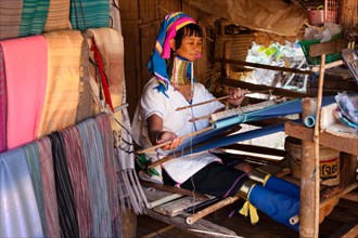 Long-necked Padaung woman wearing neck rings weaving a garment