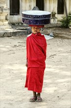 Buddhist novice carrying a box on his head