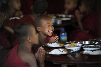 Buddhist novices praying before eating their meal in a monastery