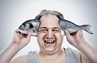 Chubby man holding a fish next to his head