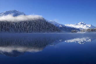 Snowy Piz da la Margna mountain being reflected in lake Champferersee