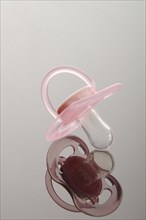 Pink pacifier on a reflective surface