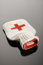 Hot water bottle in a woolen bag with a red cross