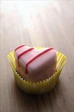 Pink heart-shaped petit four on a wooden surface