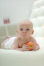 Baby lying on his stomach with an apple