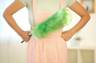Housewife wearing an apron and holding a feather duster