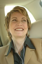 Business woman wearing headphones in a car