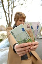 Businesswoman holding fanned out euro banknotes
