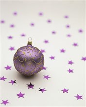Purple Christmas bauble lying on purple stars