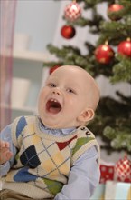 Toddler singing in front of a Christmas tree