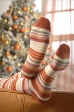 Woman's feet in stripy socks lying on a sofa at Christmas time