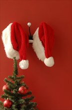 Two Santa hats hanging on nostalgic coat hooks
