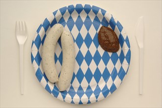 Weisswurst veal sausage with mustard on a paper plate with the Bavarian diamond pattern