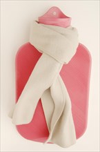 Pink hot water bottle with a winter scarf