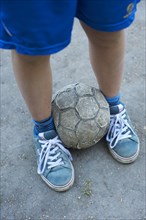 Detailed view of children legs with an old football