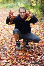 Man playing with autumn leaves