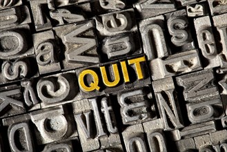 Old lead letters forming the word 'QUIT'