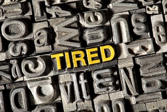 Old lead letters forming the word "TIRED"