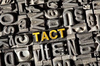 Old lead letters forming the word 'TACT'