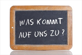 Old school blackboard with the words WAS KOMMT AUF UNS ZU?