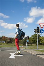 Boy with a school bag and a skateboard on a street