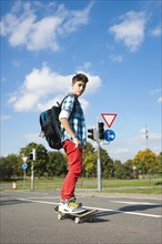 Boy with a school bag and a skateboard on a street
