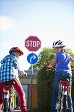 Boy and girl waiting with their bicycles in front of a stop sign