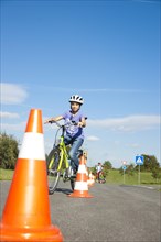 Children practicing to ride slalom on a bicycle at a traffic awareness course