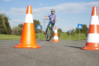 Child practicing to ride slalom on a bicycle at a traffic awareness course