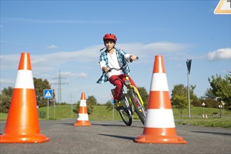 Child practicing to ride slalom on a bicycle at a traffic awareness course