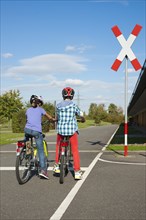 Children waiting with their bicycles in front of a railroad crossing at a traffic awareness course