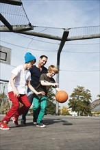 Two cool boys playing basketball with their father