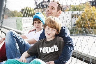 Two cool boys sitting with their father on a playground