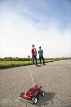 Two boys playing with a remote-controlled model car