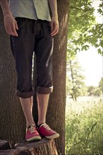 Lower section of young man standing on a tree stub