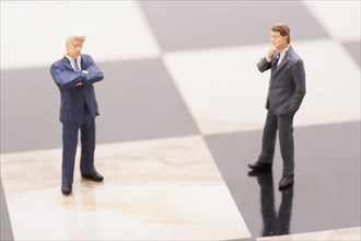 Figurines of businessmen standing on a chess board