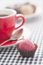 Chocolate truffle beside to a red coffee cup