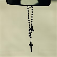 Rosary hanging from mirror in a car