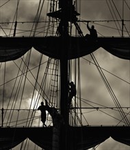 Three sailors on the mast of a ship