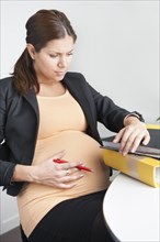 Pregnant woman sitting in an office looking troubled