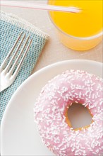 Donut with sprinkles and a glass of orange soda