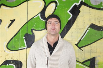 Man standing in front of wall covered with graffiti