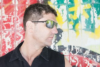 Portrait of a man standing in front of wall covered with graffiti