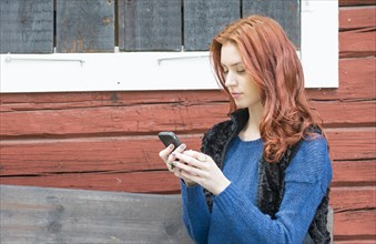 Young woman with red hair looking at a message on her smartphone