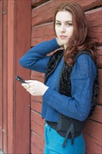 Young woman with red hair holding a smartphone