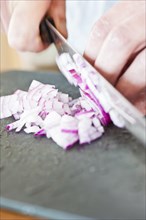Red onion being cut on a plastic cutting board