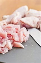 Cut up pieces of uncooked chicken on a plastic cutting board